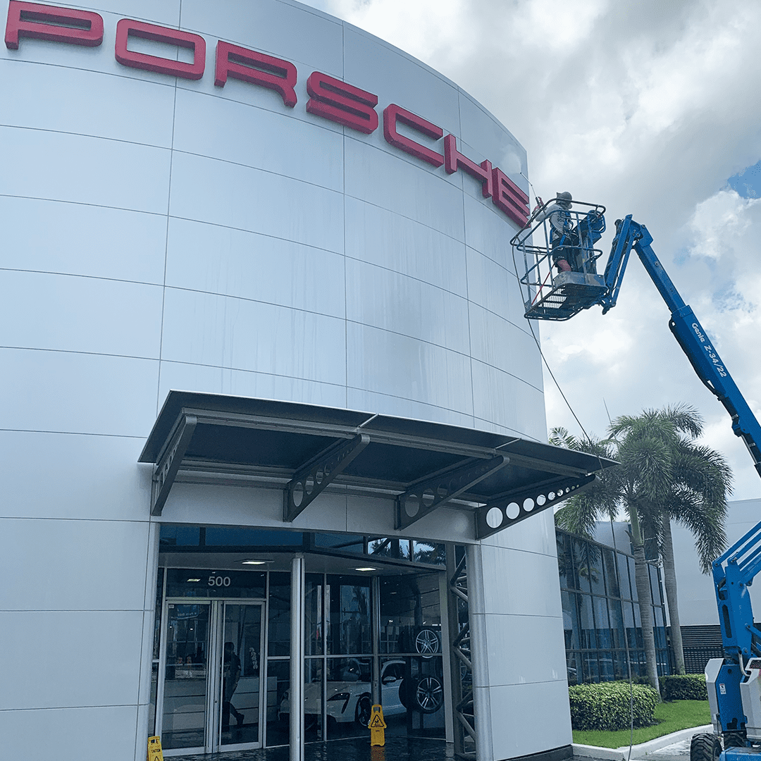 Aqua Force boom lift working the facade of a car dealership